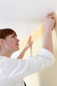 woman putting up a wallpaper border