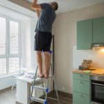Man preparing to paint ceiling while on a ladder
