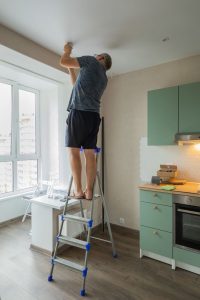 Man preparing to paint ceiling while on a ladder