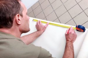 man measuring wallpaper